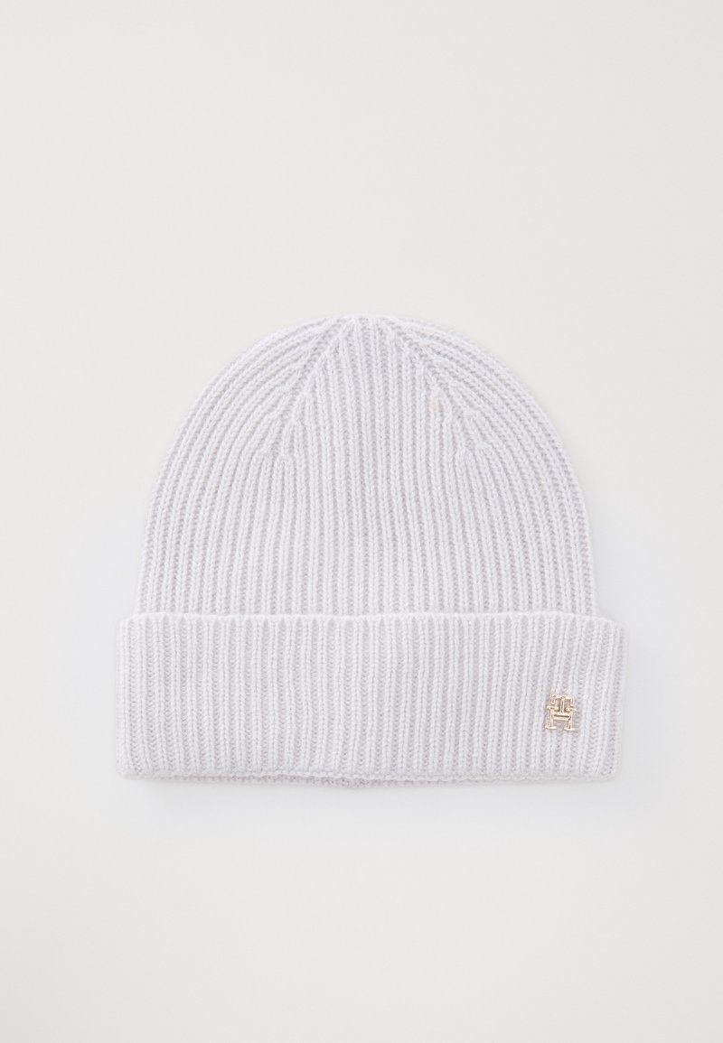 Un bonnet en tricot côtelé gris clair avec un revers et un petit accent de logo doré. Texture douce et design ajusté.