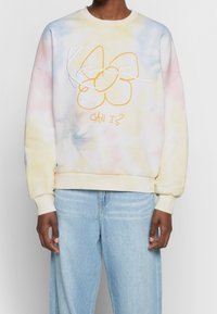 Katoenen sweatshirt met een pastel tie-dye patroon in geel, roze en blauw. Heeft een speelse afbeelding en de tekst "KAN IK?" in oranje.