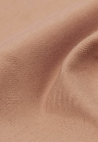 Látka v broskvové barvě se hladkým, texturovaným povrchem a jemným žebrováním, složená a volně rozprostřená, aby ukázala hloubku a měkkost.