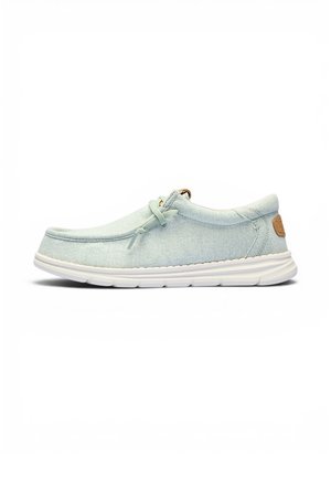 Zapato informal azul claro tipo mocasín con suela blanca, detalle de cordones en el lateral y parche de cuero marrón en el talón, visto desde el lado izquierdo.