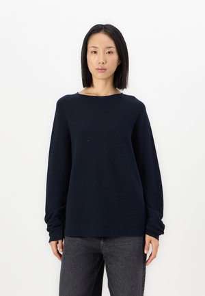 Granatowy sweter z długim rękawem o luźnym kroju, szerokim dekolcie i teksturowanej tkaninie. Poł�ączony z ciemnymi dżinsami. Prosty, minimalistyczny design.