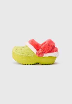 Sabot en velours vert lime de l'enfant avec une doublure en peluche rose corail et un liseré blanc, présentant un bouton rouge en forme de cœur sur le côté.