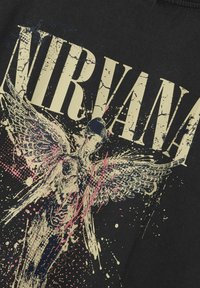Sorte T-shirt med stort "NIRVANA" tekst og abstrakt engel grafisk design. Har splattermønstre i pink og hvid mod en struktureret sort baggrund.