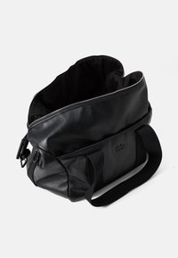 Black leather bag with a top zipper, spacious interior, two sturdy handles, and a subtle logo embossed on the side.