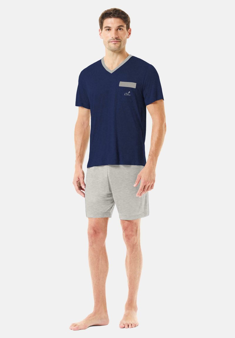 Camiseta de manga corta de cuello en V en azul marino con detalles en gris y bolsillo, combinada con pantalones cortos gris claro. Tejido suave, ajuste casual.