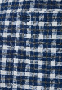 Granatowo-biała tkanina w kratę o teksturowanym wykończeniu. Charakteryzuje się małymi kwadratami i akcentami w postaci przeszyć; zawiera dyskretny detal w postaci płaskiej kieszeni.