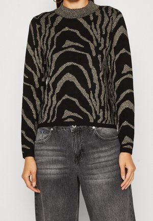 Maglione nero a maglia con motivo zebra metallico oro, dotato di colletto rotondo e maniche lunghe, abbinato a jeans in denim grigio.