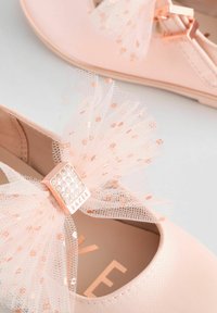 Ballerine rosa con un fiocco in rete, dettagli in oro rosa e decorazioni scintillanti. Materiale liscio e morbido con design della punta arrotondata.