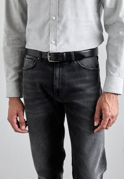 Camisa de botón gris combinada con cinturón de cuero negro y jeans gris oscuro, con una textura suave y un ligero desgaste.