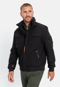 Black insulated jacket with a zip front, high collar, and multiple pockets. Features ribbed cuffs and a contrasting fabric lining.
