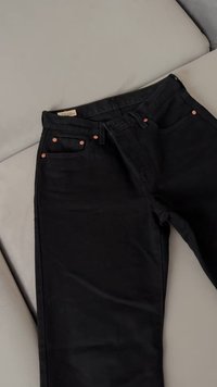 Črne denim hlače s prilegajočim dizajnom, opremljene s kovinskimi dodatki v bakreni barvi in petimi žepi. Gladka tekstura s podrobnostmi šivanja.
