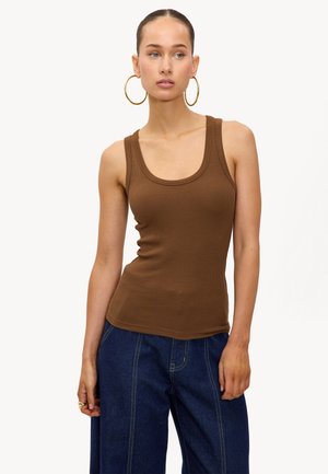 Débardeur marron à rayures avec un décolleté arrondi et une coupe ajustée, associé à un pantalon en jean bleu taille haute. Boucles d'oreilles en or visibles.