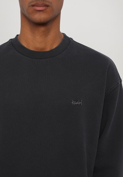 Sweatshirt noir à col rond en coton. Présente un col côtelé et un logo brodé discret sur la poitrine gauche. Texture douce et coupe décontractée.