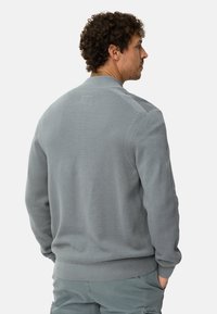 Grijze gebreide trui met een gestructureerde afwerking, geribde kraag en manchetten, met subtiele branding aan de achterkant. Getailleerde pasvorm, casual ontwerp.