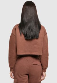 Bruine cropped sweatshirt met een ronde halslijn, geribbelde manchetten en bijpassende sweatpants met een zak en subtiele textuur.