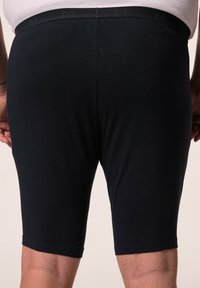 Schwarze Stretch-Shorts mit glatter Textur, die ein dezentes Logo am elastischen Bund aufweisen und für Komfort und Passform konzipiert sind.
