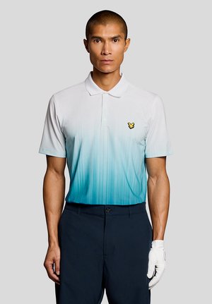 Mand iført poloshirt med hvid-til-blå gradient, mørke bukser og hvid golvhandske på højre hånd, stående foran en ensfarvet grå baggrund.