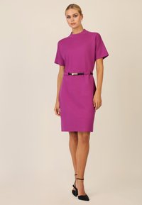 Vestido morado de manga corta con un cuello alto, ceñido en la cintura con un cinturón negro; textura suave y diseño hasta la rodilla.