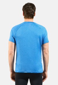 T-shirt de sport bleu à manches courtes, fabriqué en tissu texturé et évacuant l'humidité. Présente des coutures plates et un col rond.