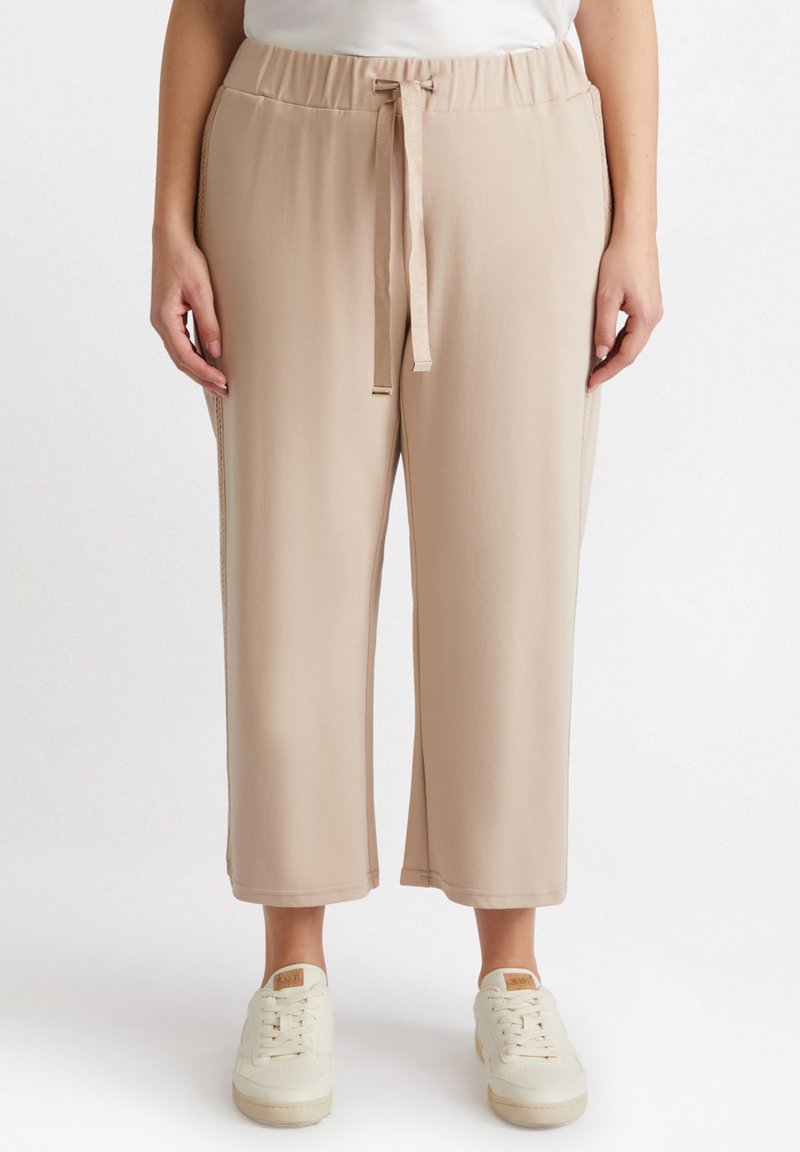 Beige, lätta, högmidjade byxor med dragsko. Har sidofickor och en avslappnad, kort passform. Matchas med vita sneakers.