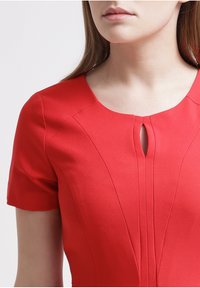 Rode jurk met korte mouwen, voorzien van een keyhole-halslijn, gestructureerde stof en verticale naaddetails voor een getailleerde pasvorm.