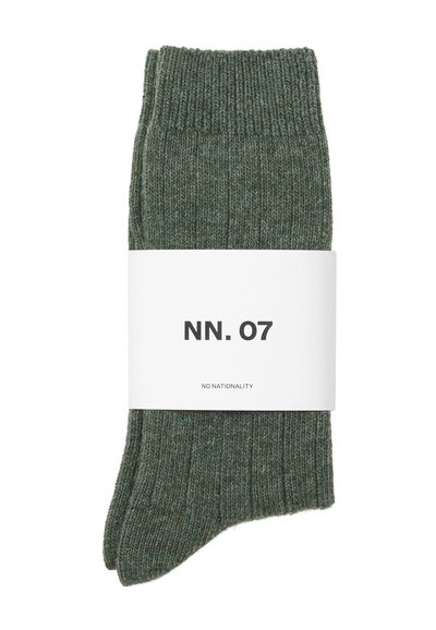 Grüne Strümpfe aus Strick mit einem gerippten Muster und einem gefalteten Bündchen, gesichert mit einem weißen Etikett, auf dem "NN. 07" und "NO NATIONALITY" steht.