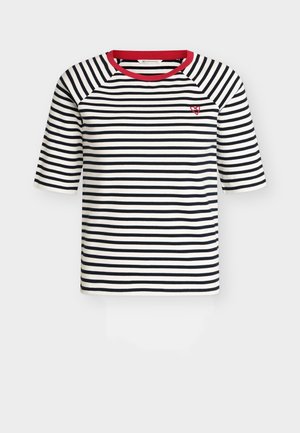 Μπλούζα με οριζόντιες λωρίδες σε ναυτικό μπλε και άσπρο, με κόκκινο στρογγυλό λαιμόκοψη και μικρή κόκκινη καρδιά κεντημένη στο επάνω αριστερό μέρος του στήθους.