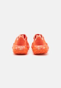 Klar oransje joggesko med teksturerte strikkoverdeler, gummisåler og en camo-print detalj på hælen. Stilfull bakdesign.