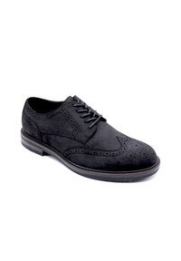 Chaussure brogue en suede noir avec fermeture à lacets, perforations décoratives sur le dessus, bout rond et semelle en caoutchouc contrastante.