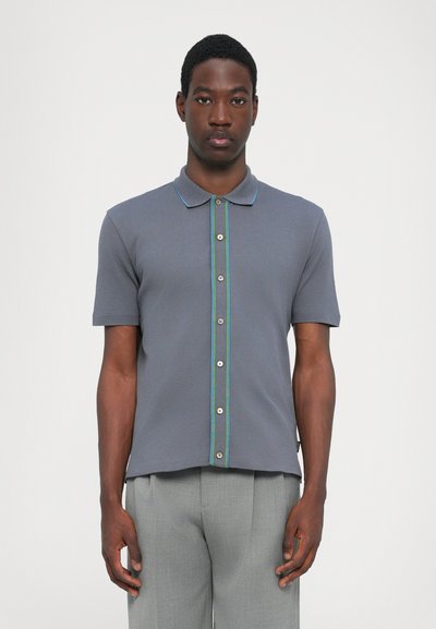Polo à manches courtes en gris, avec un devant boutonné et des accents verts et bleus, fabriqué à partir d'un tissu lisse et texturé.