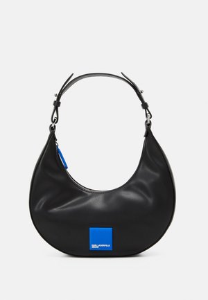 Zwarte leren handtas met een gebogen vorm, ritssluiting en een blauw vierkant logo accent. Voorzien van een verstelbare schouderband.