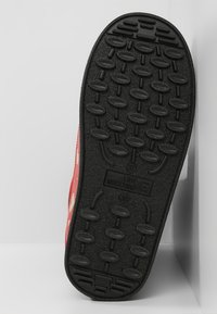 Red rubber sneaker sole with textured black tread. Features "LOVE MOSCHINO" branding and size marking, designed for grip and durability.