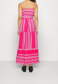Robe maxi en coton rose vif avec un motif de formes géométriques. Bretelles spaghetti et détail de taille élastique.