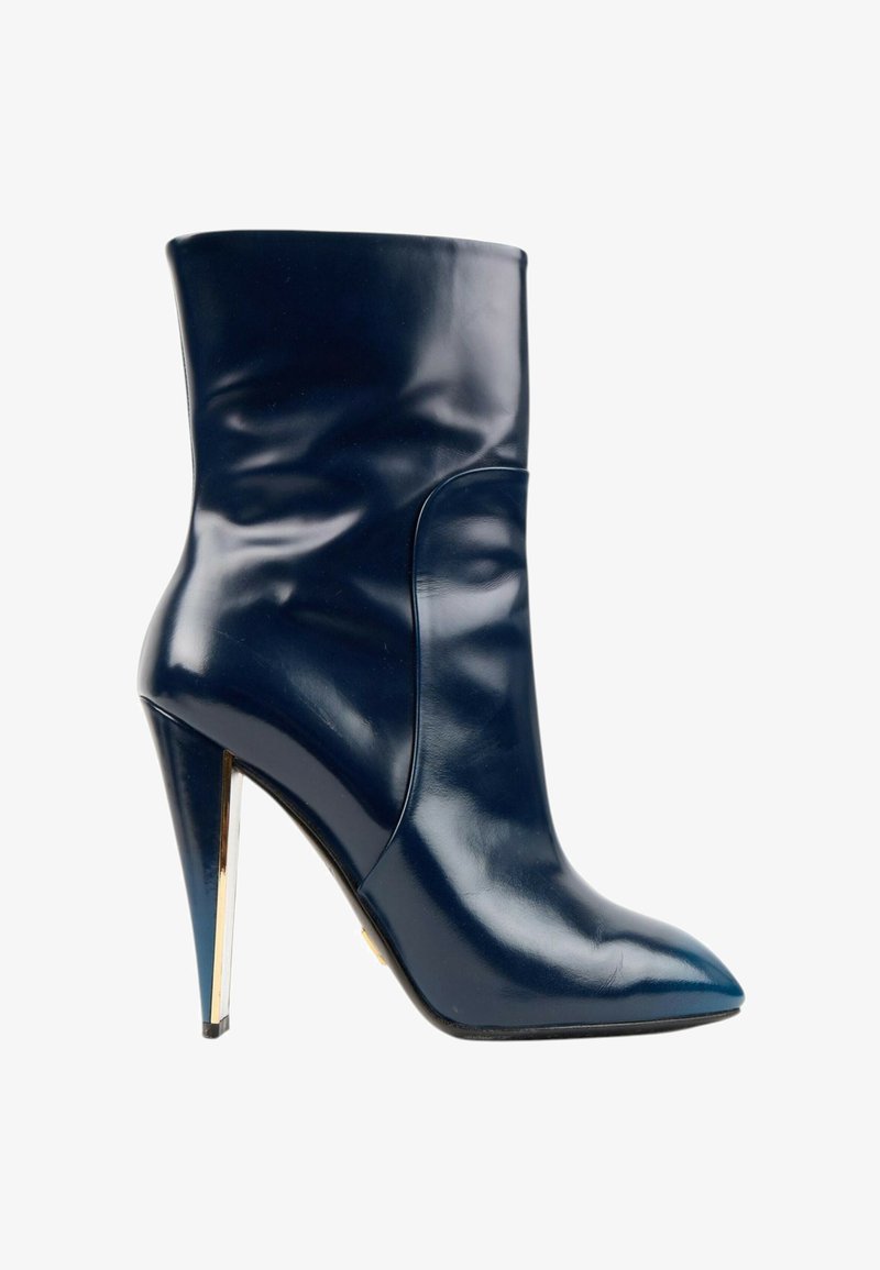 Bottine à talon haut bleu foncé brillant avec bout pointu et talon aiguille fin présentant un accent métallique doré, vue de profil.