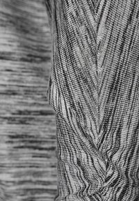 Szary i czarny dzianinowy materiał o wzorze zygzakowatym, z teksturowaną powierzchnią i gładkim wykończeniem. Nadaje się do codziennego noszenia lub na sport.