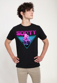 Černé bavlněné tričko s barevnou grafikou medvěda a textem "SOOTY", živý tyrkysový trojúhelník a vzory hudebních not.