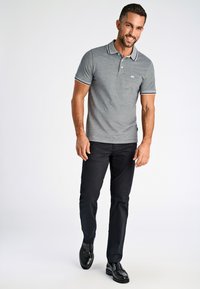 Grå polo t-shirt med klassisk krage, med kontrasterande svart kant. Matchar med mörka byxor och polerade svarta skor.
