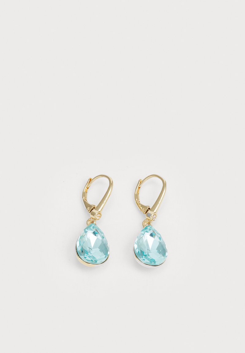 Brincos em tom dourado apresentando grandes cristais em forma de gota de água, de um azul claro, com superfície facetada. Pequenas pedras redondas de acento acima dos ganchos.