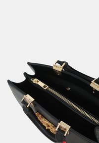 Borsa a tracolla in pelle nera con dettagli in oro, due scomparti e tasca con zip. Presenta manici testurizzati e un accento decorativo all'interno.