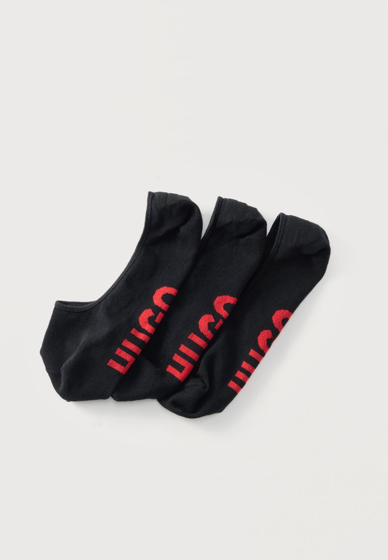 Trois chaussettes no-show noires avec le texte rouge "Wilson" empilées côte à côte sur un fond blanc.