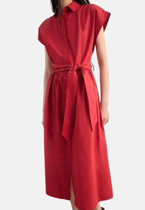Robe-chemise rouge à manches courtes avec un devant boutonné et une ceinture assortie à la taille. Tissu lisse, longueur genou, avec une fente latérale.