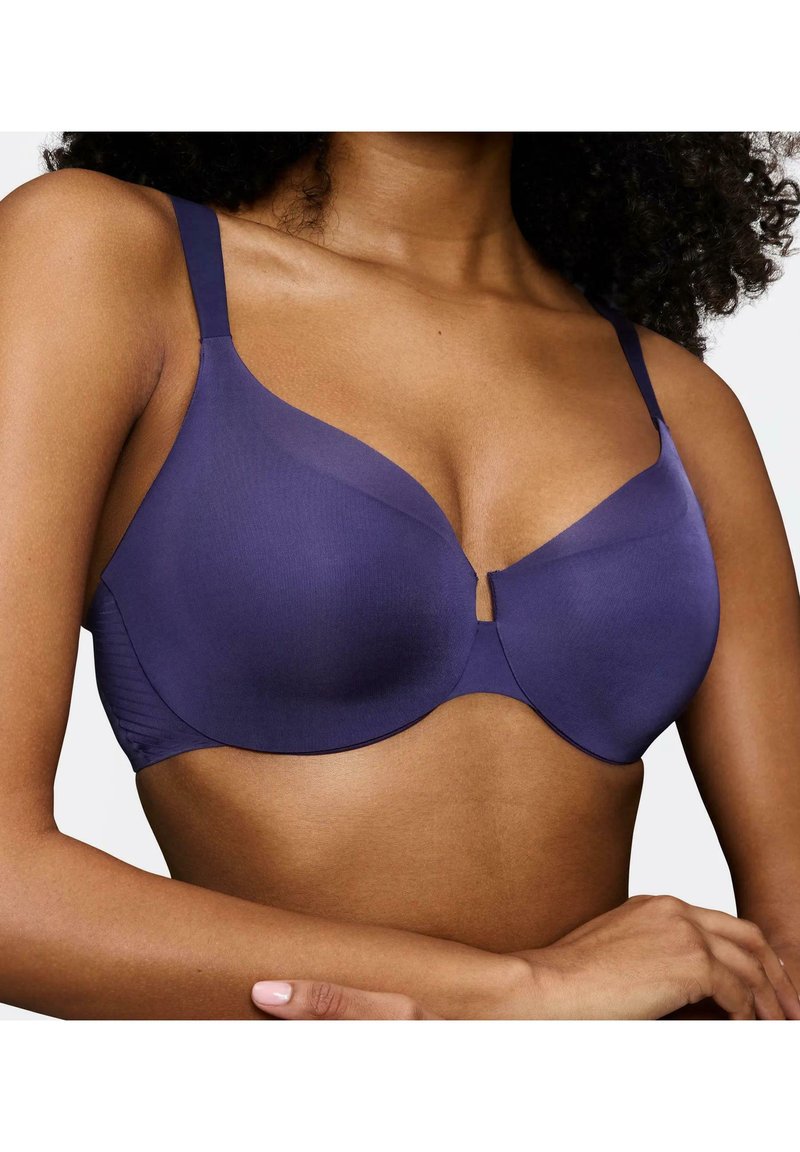 Fioletowy biustonosz z gładkiego materiału, z fiszbinami i regulowanymi ramiączkami. Posiada subtelny szczegół w formie dziurki w centrum z przodu oraz bezszwowe miseczki.