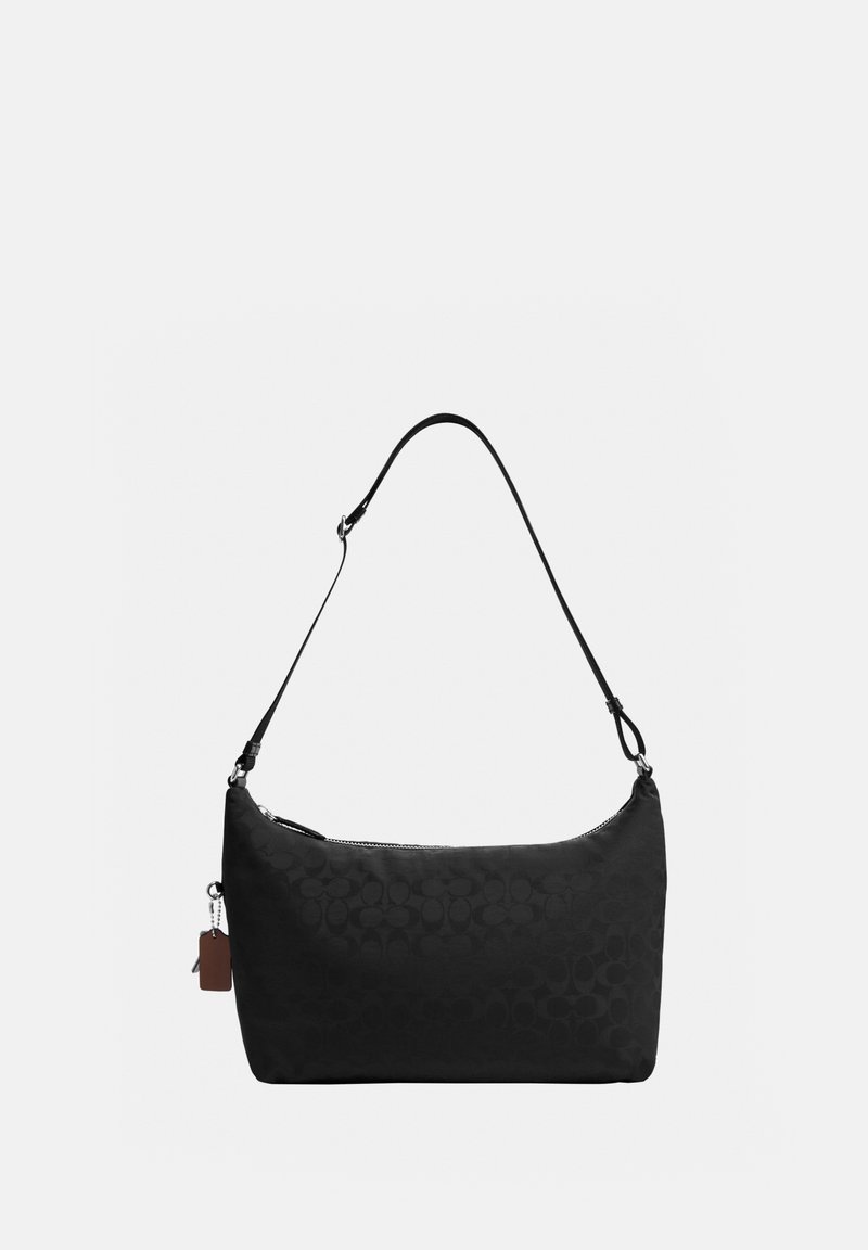 Bolso de hombro negro con correa ajustable, patrón circular sutil, cierre de cremallera y pequeña etiqueta de cuero adherida sobre un fondo liso.