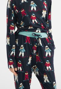 Námořnický pyžamový set se vzorem lyžařů, vyrobený z měkké látky, s dlouhými rukávy a elastickým pasem s aqua šňůrkou.