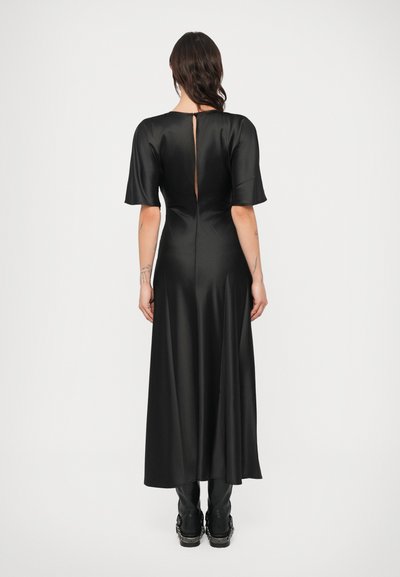 Čierne saténové šaty s krátkymi rozšírenými rukávmi, detailom v tvare otvoru na chrbte a voľnou siluetou s dĺžkou do polovice lýtok.