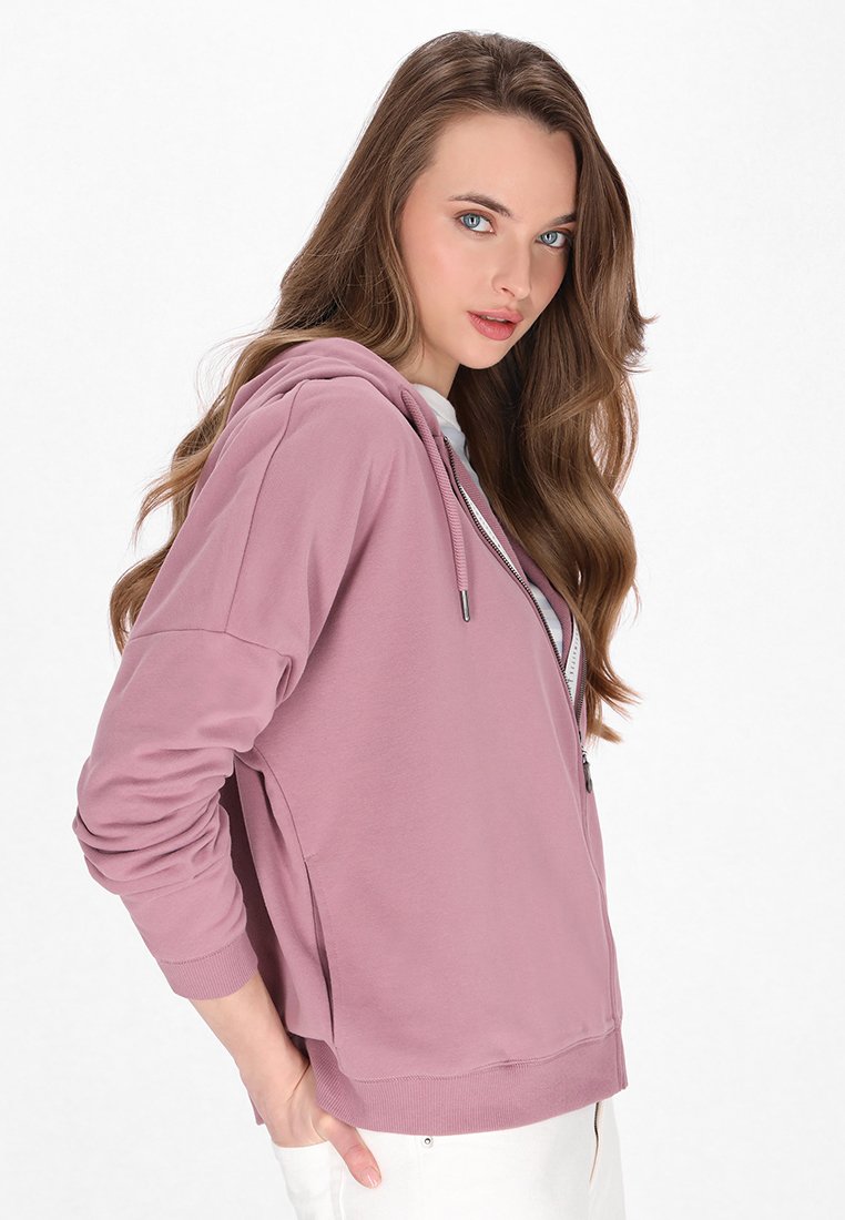 Helle pinke Zip-up-Hoodie mit Kapuze mit Kordelzug, gerippten Bündchen und legerem Schnitt. Hergestellt aus weichem Stoff, mit seitlichen Taschen und glatter Textur.