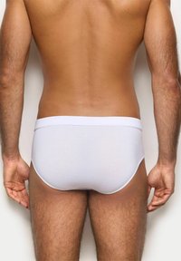 Mutande bianche in stile slip con una texture liscia e una cintura elastica, caratterizzate da un design aderente e dettagli di cucitura minimi.