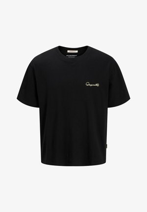 Dreng stående iført sort t-shirt, lyseblå denimshorts, hvide sokker og sort-hvide sneakers på ensfarvet hvid baggrund.