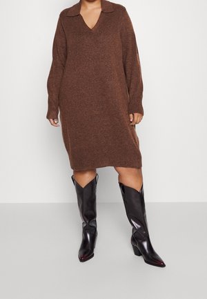 Person wearing a brown long-sleeve knit dress with a collar and black mid-calf pointed-toe heeled boots against a plain background.