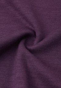 Tessuto di maglia viola con una texture liscia, che mostra fibre intrecciate, drappeggiando per creare morbide pieghe e un motivo vorticoso.